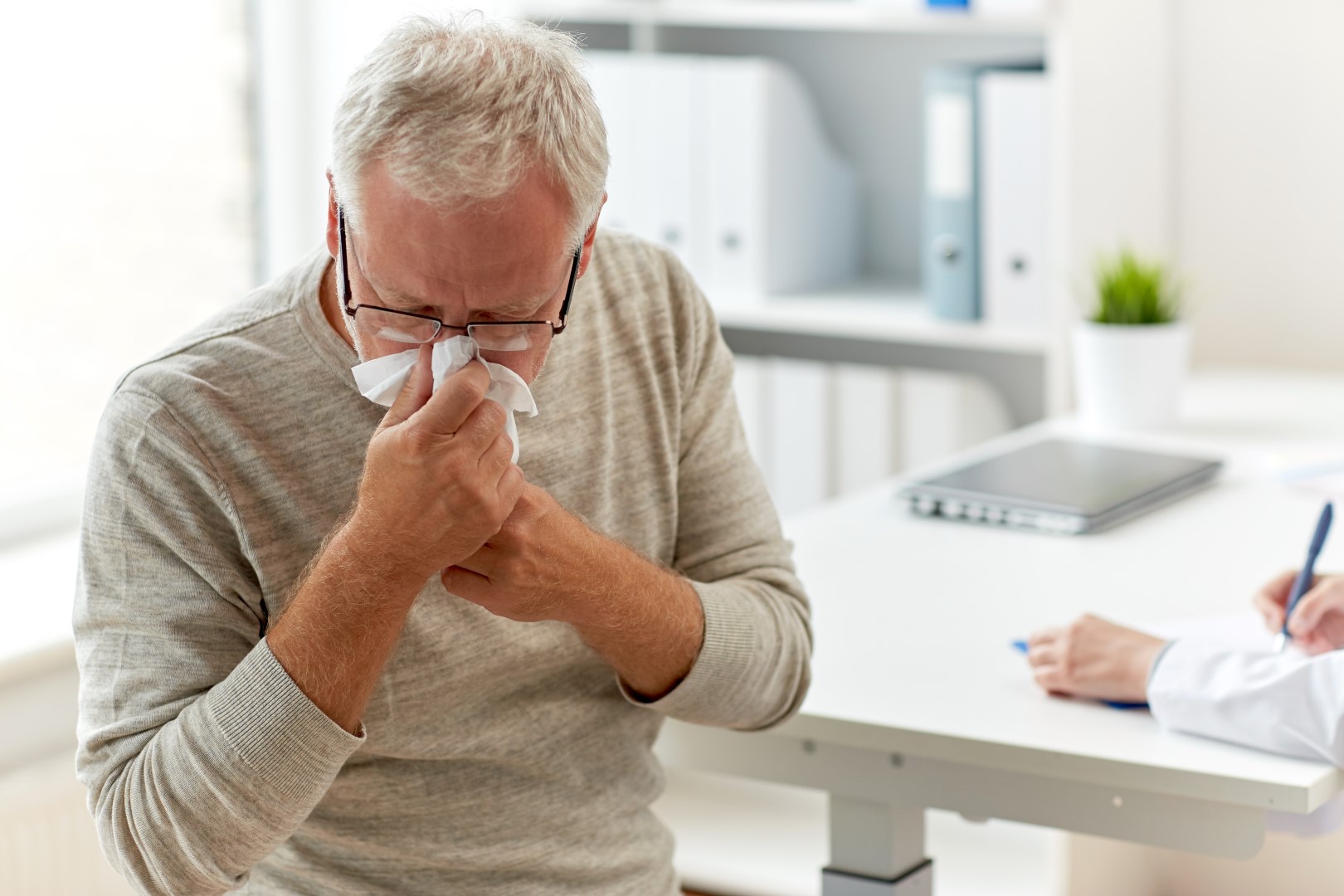senior man blowing nose with napkin at hospital